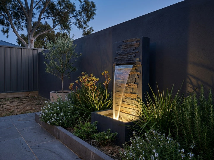 Calm Water Feature in a paved Adelaide courtyard at dusk, water running and its integrated LED lighting glowing