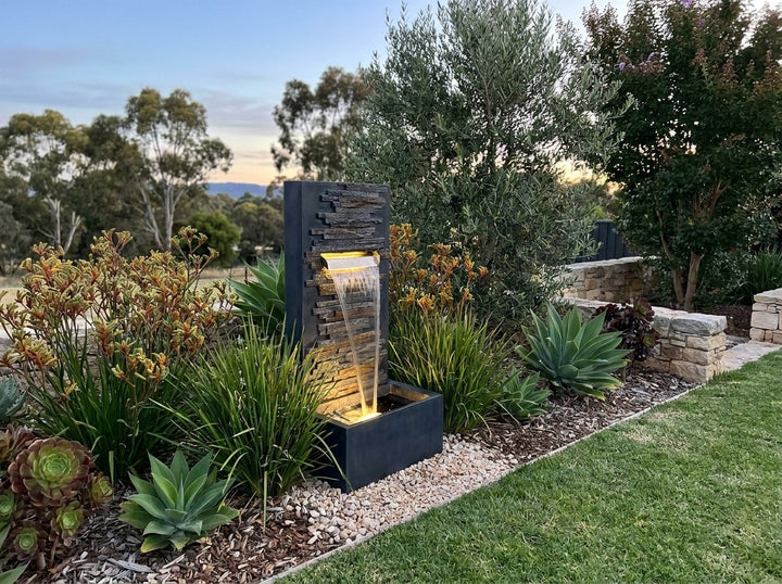 Calm Water Feature in an established Adelaide Hills garden at dusk, water running and its integrated LED lighting glowing