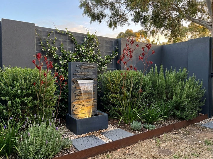 Calm Water Feature in a small city townhouse garden at dusk, water running and its integrated LED lighting glowing