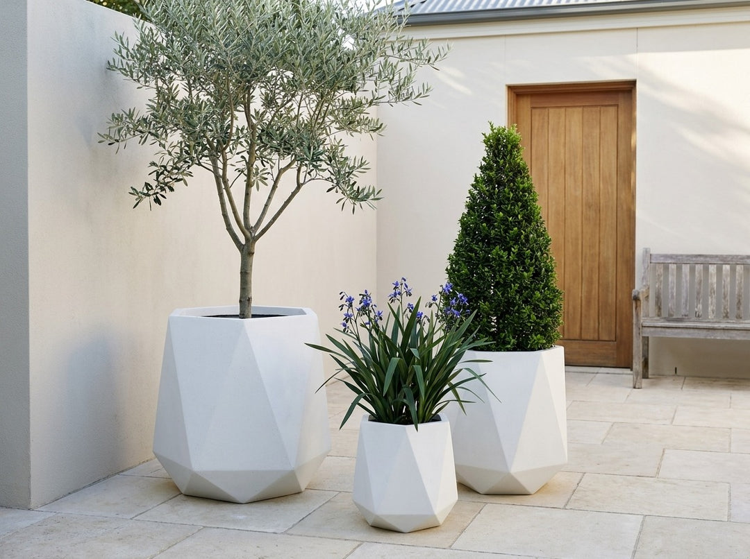 Geo Tall Arctic white terrazzo faceted planter pots in three sizes in a walled limestone courtyard