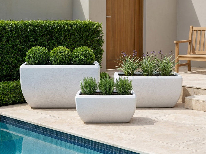 Montego Blizzard white terrazzo trough planters in three sizes on a poolside terrace