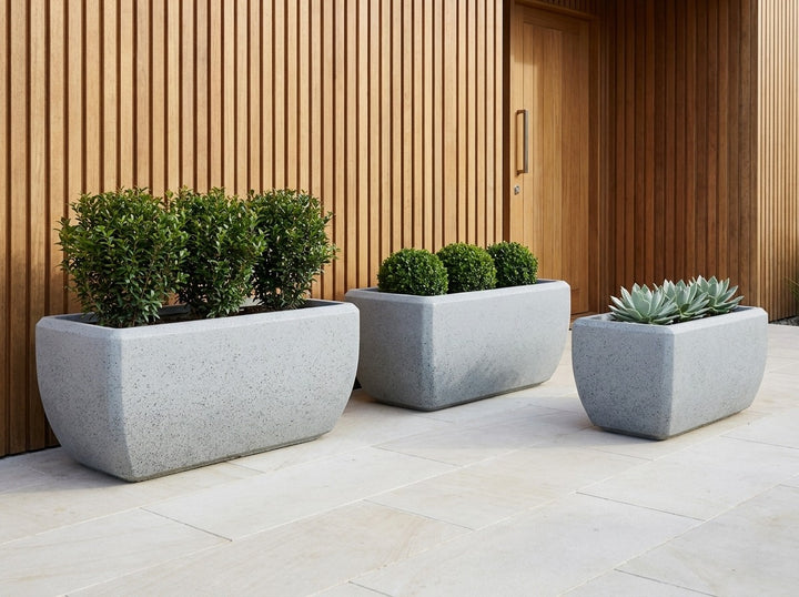 Montego Granite grey terrazzo trough planters in three sizes in a modern entry courtyard