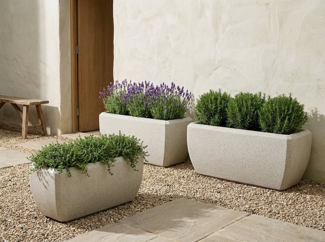Montego Nougat sand-grey terrazzo trough planters in three sizes in a Mediterranean courtyard