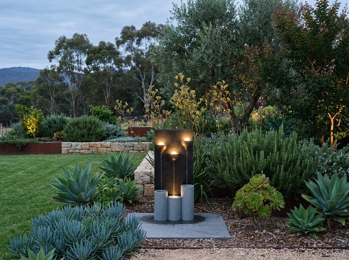 Serenity Water Feature in an established Adelaide Hills garden at dusk, water running and its integrated LED lighting glowing