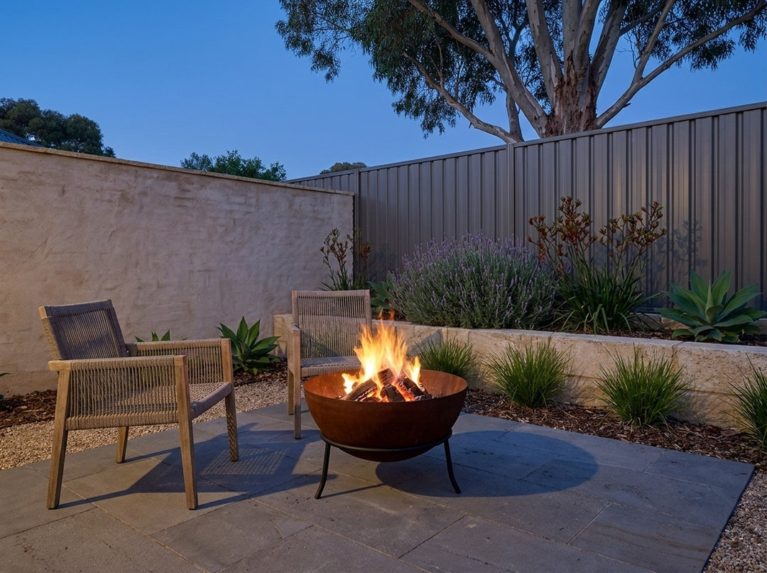 Steel Fire Pit, 61 cm across and 43.5 cm high, burning in a paved Adelaide courtyard at dusk with chairs drawn up around it