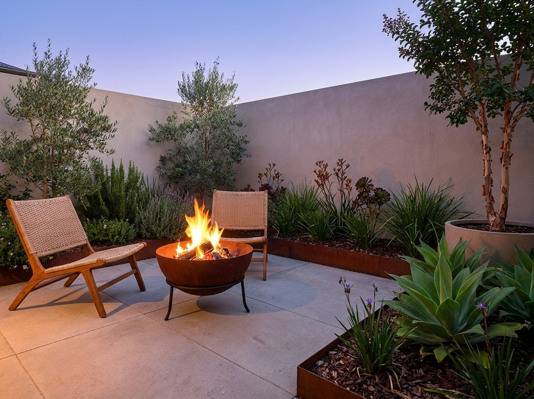 Steel Fire Pit, 61 cm across and 43.5 cm high, burning in a small city courtyard at dusk with chairs drawn up around it
