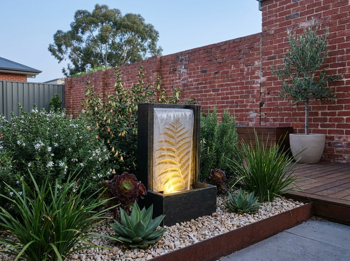 Tranquility Water Feature in a paved Adelaide courtyard at dusk, water running and its integrated LED lighting glowing