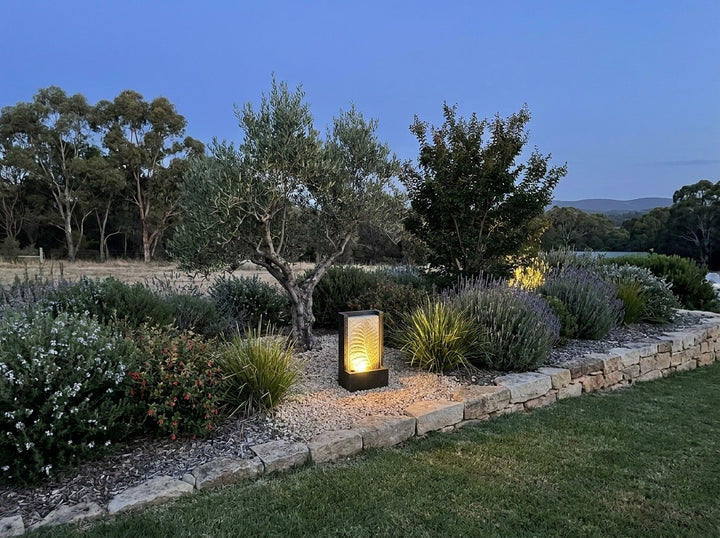 Tranquility Water Feature in an established Adelaide Hills garden at dusk, water running and its integrated LED lighting glowing