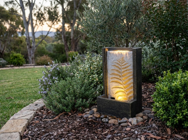 Tranquility Water Feature in an established Adelaide Hills garden at dusk, water running and its integrated LED lighting glowing