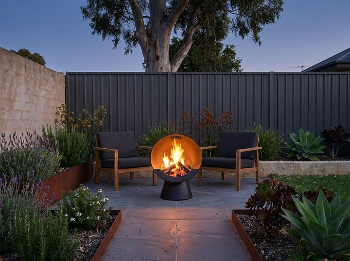 Upright Fire Pit, 61 cm across and 74.5 cm high, burning in a paved Adelaide courtyard at dusk with chairs drawn up around it