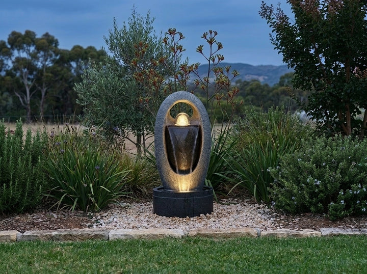 Zen Water Feature in an established Adelaide Hills garden at dusk, water running and its integrated LED lighting glowing